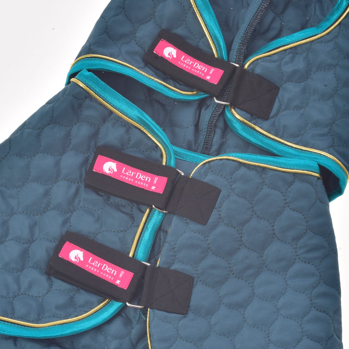 Roze LarDen-labels op de drie zwarte sluitriemen van de plat neergelegde Hobby Horse deken met afneembaar halsstuk Lagoon