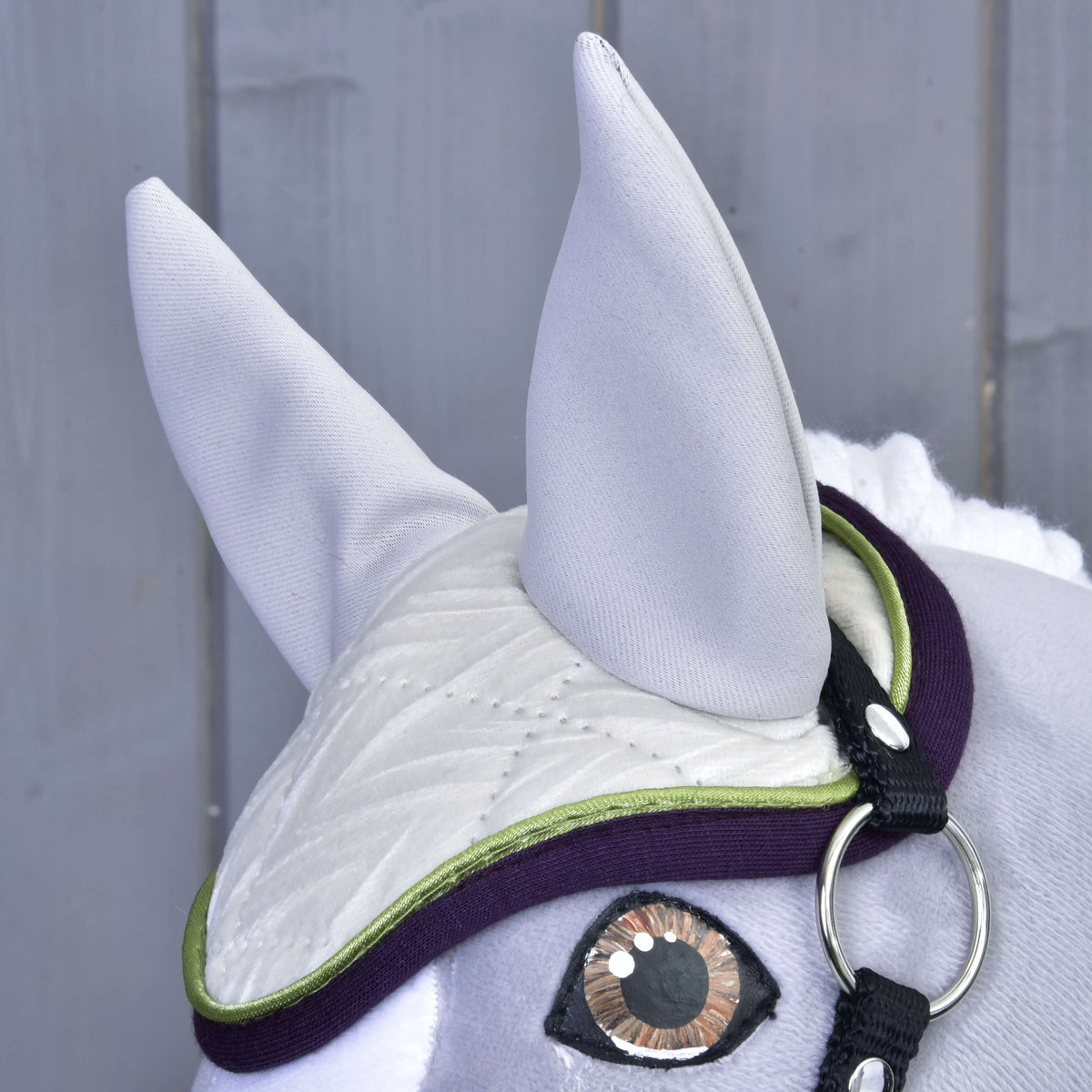 Bonnet d’oreilles de l’ensemble Leonardo sur un Hobby Horse gris : oreilles gris clair, matelassage ivoire, passepoil vert citron, bordure violette