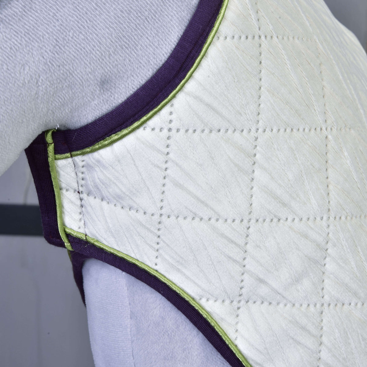 Couverture de l’ensemble Leonardo sur un Hobby Horse gris : matelassage ivoire en losanges à motif de feuilles, passepoil vert citron, bordure violette