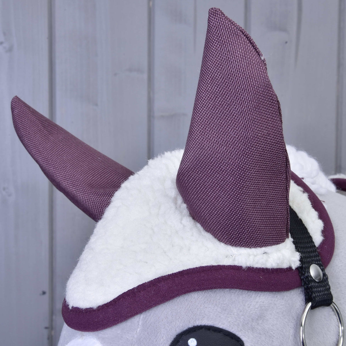 Close-up van het oornetje uit Set Loret met hoge pruimkleurige oren, zachte crèmekleurige teddy en pruimkleurige bies op een grijs hoofd