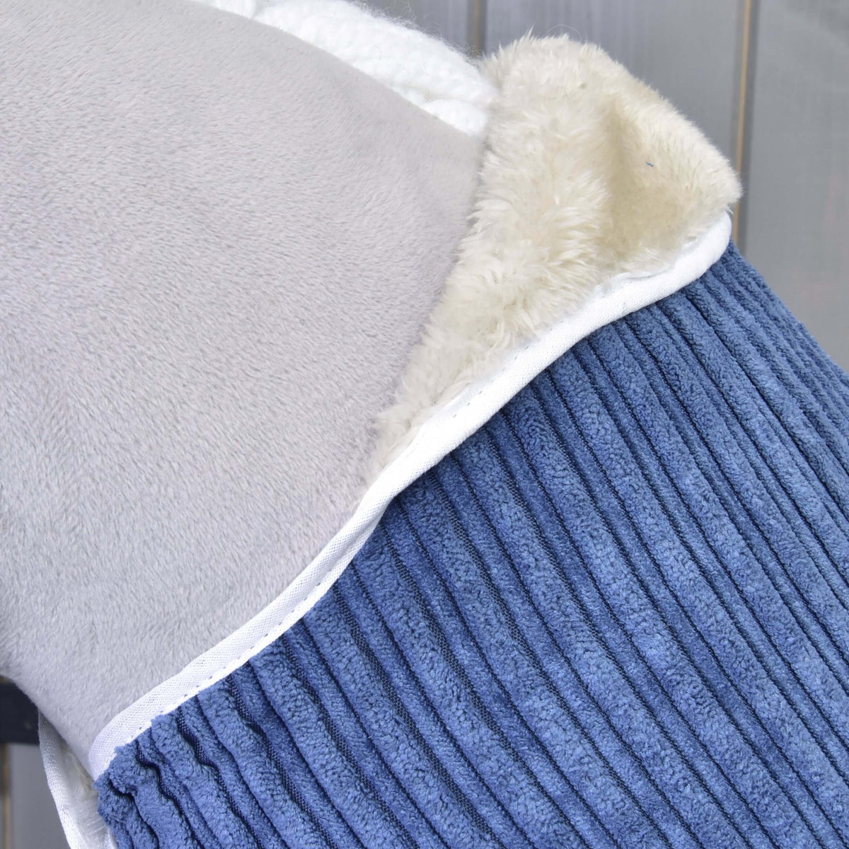 Gros plan sur l’encolure de la couverture Manchester Plum, doublure en polaire crème et passepoil blanc, sur un Hobby Horse gris
