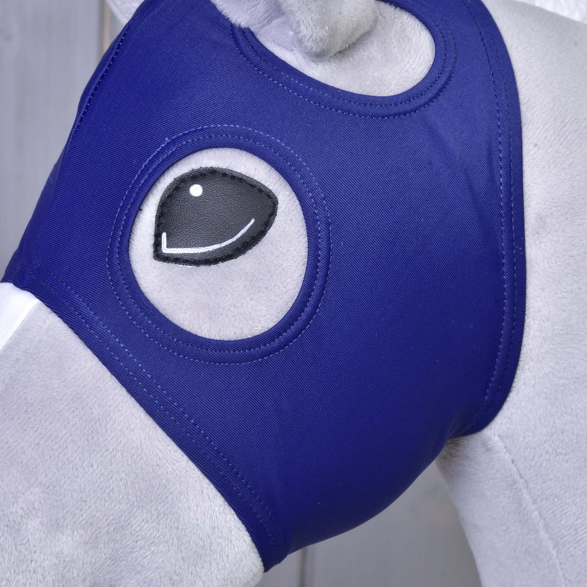 Gros plan du masque de cheval sans oreilles sur un Hobby Horse : tissu bleu marine autour de l’œil noir, l’ouverture de l’oreille au-dessus