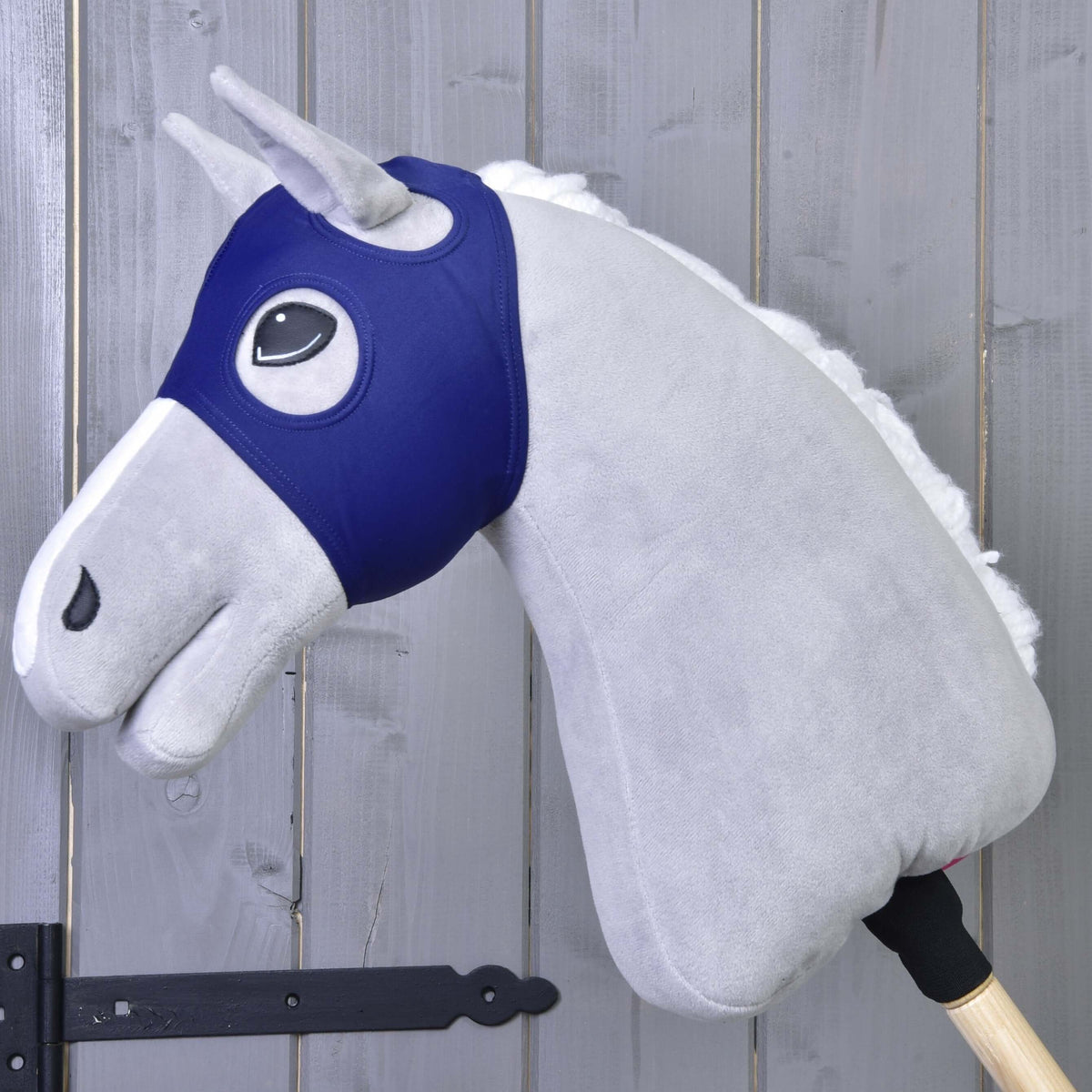 Masque de cheval sans oreilles LarDen en tissu extensible bleu marine sur un Hobby Horse en peluche gris, les oreilles passées dans les ouvertures