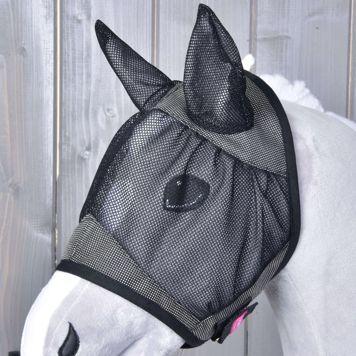 Masque anti-mouches De Luxe Gris pour Hobby Horse de près sur une tête gris clair : oreilles en maille noire, filet des yeux et petite étiquette rose
