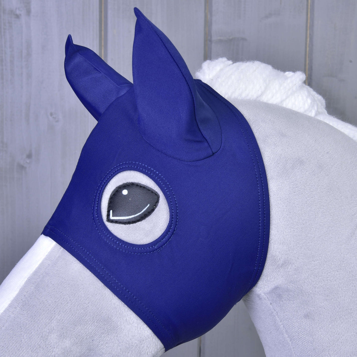 Close-up van het paardenmasker met marineblauwe stoffen oren op een grijze Hobby Horse, de opening rond het zwarte oog