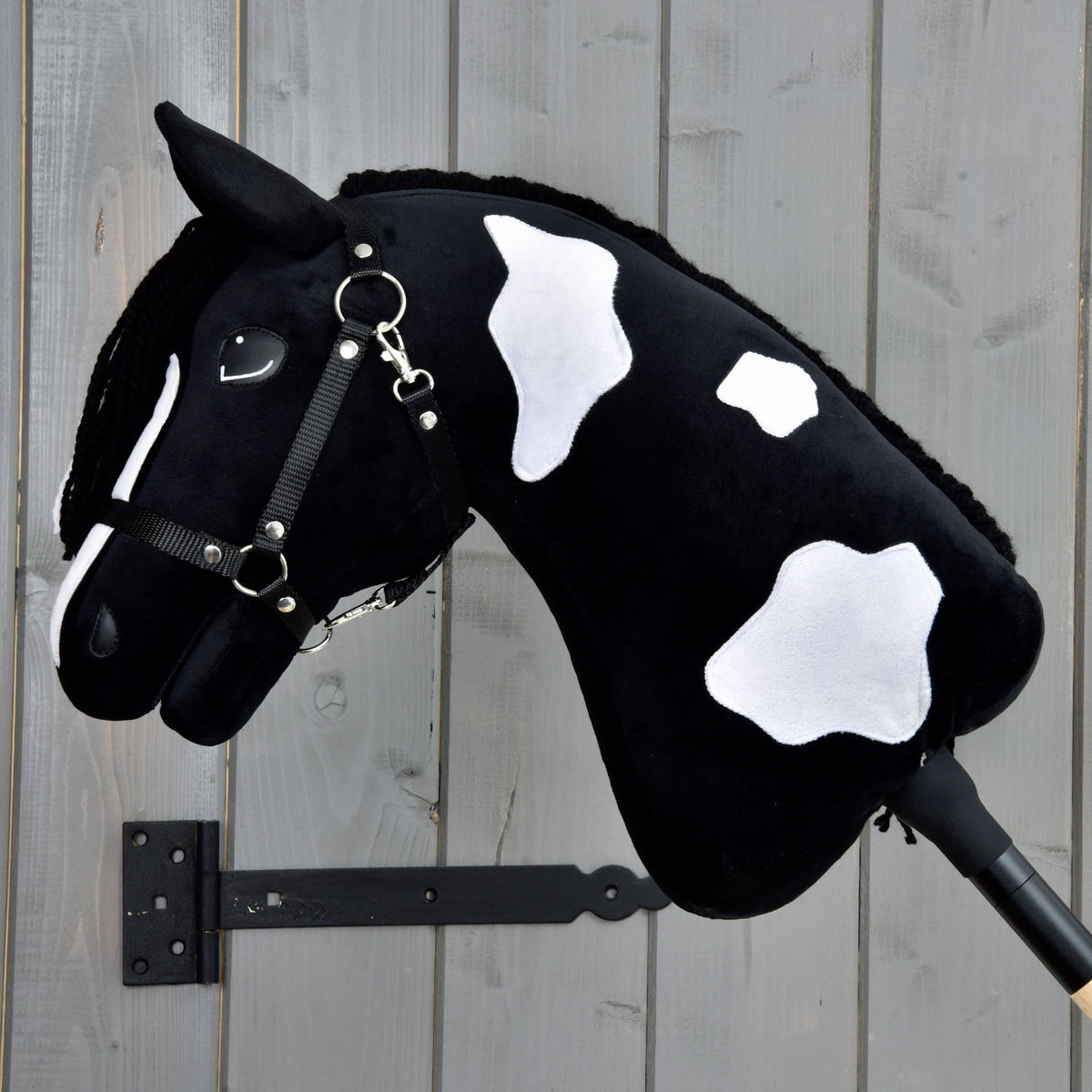 Hobby Horse Merlin with Black Halter showing three white patches on its black neck, mane on the far side