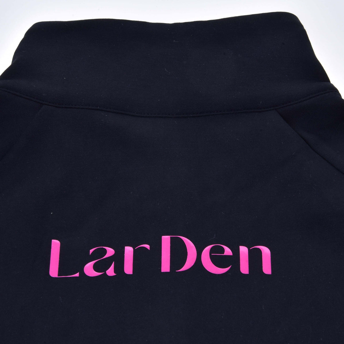 Close-up van de achterkant van de Hobby Horse LarDen sweatshirt: grote roze letters onder de zwarte opstaande kraag