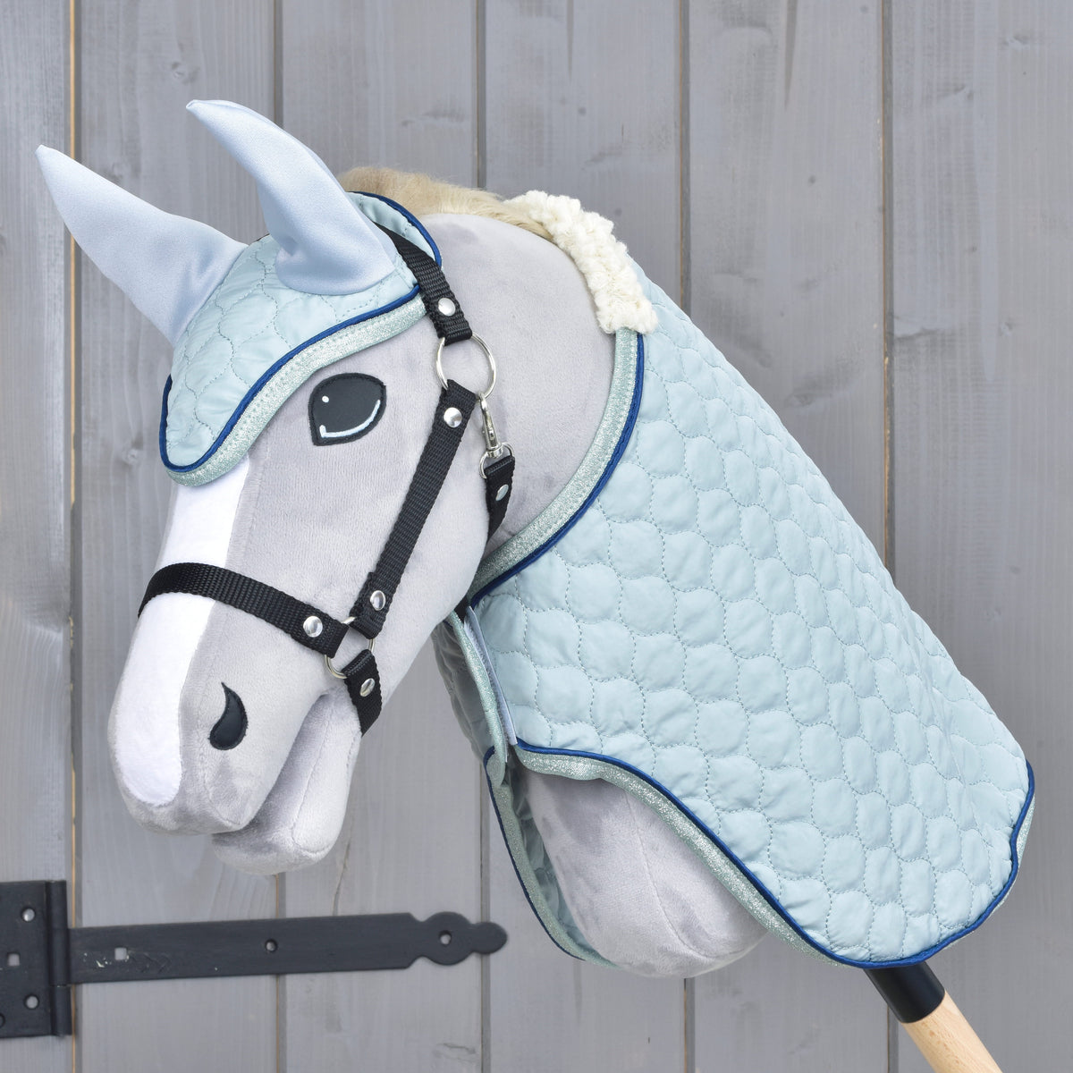 Hobby Horse gris au licol noir portant l'ensemble Mint : couverture et bonnet d'oreilles matelassés bleu pâle, passepoil marine