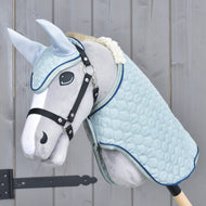 Hobby Horse gris au licol noir portant l'ensemble Mint : couverture et bonnet d'oreilles matelassés bleu pâle, passepoil marine