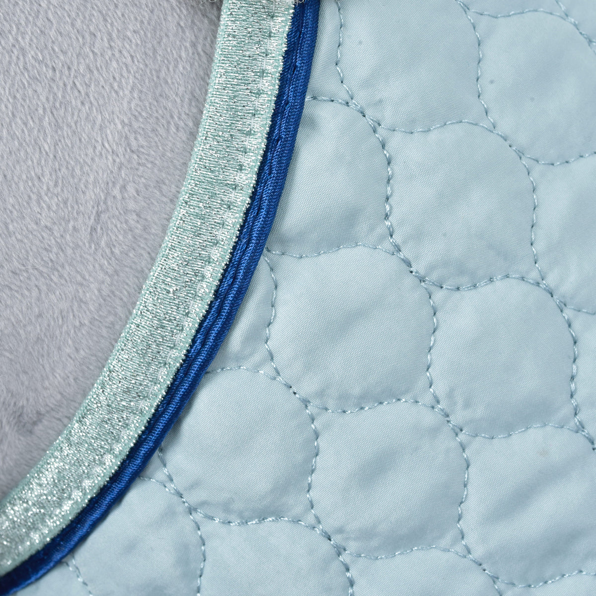 Macro du matelassage arrondi, du passepoil bleu roi et de la bordure pailletée menthe sur la couverture bleu pâle de l'ensemble Mint pour Hobby Horse