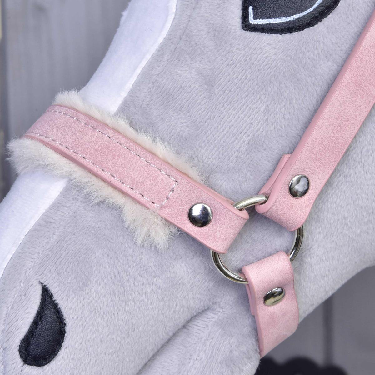 Gros plan sur la muserolle vieux rose avec fourrure crème, fines surpiqûres et anneau argenté sur un Hobby Horse gris