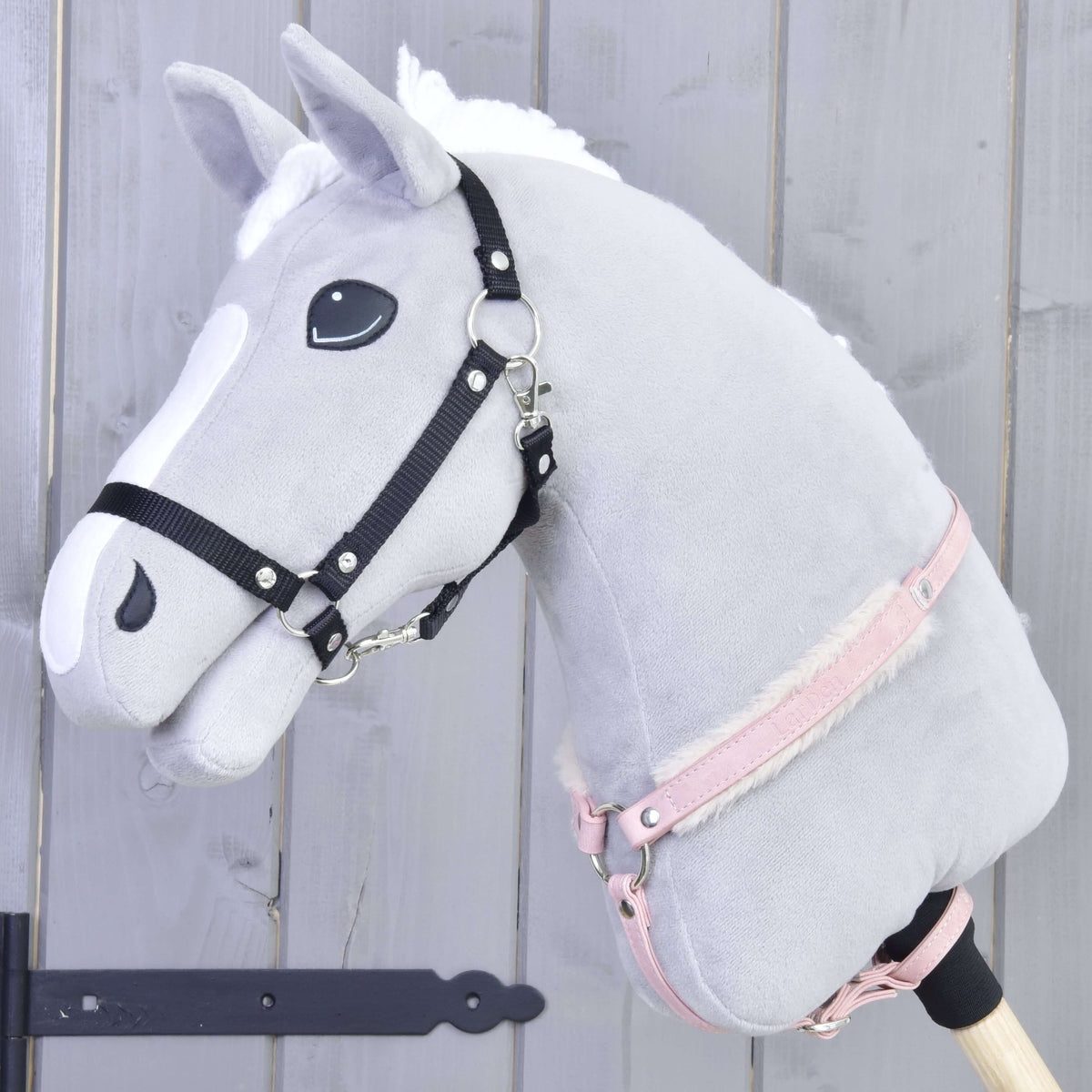 Hobby Horse gris avec licol noir portant la sangle de poitrail rose en similicuir avec fourrure autour de l’encolure