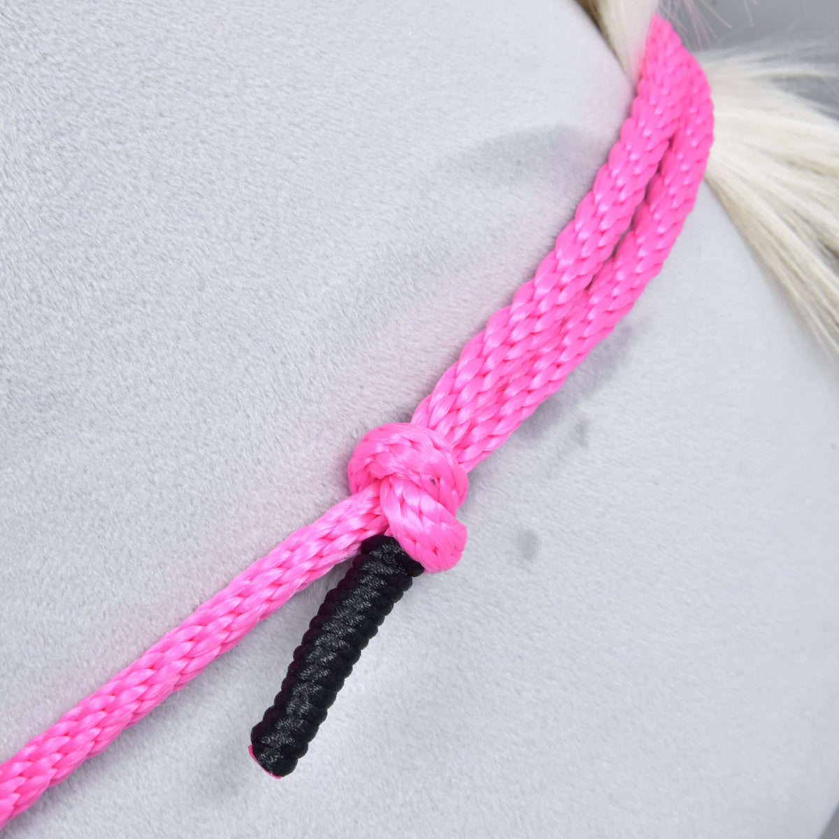 Gros plan sur la corde tressée rose du cordéo Pink Festive, avec nœud et extrémité enroulée de noir, sur une encolure grise en peluche