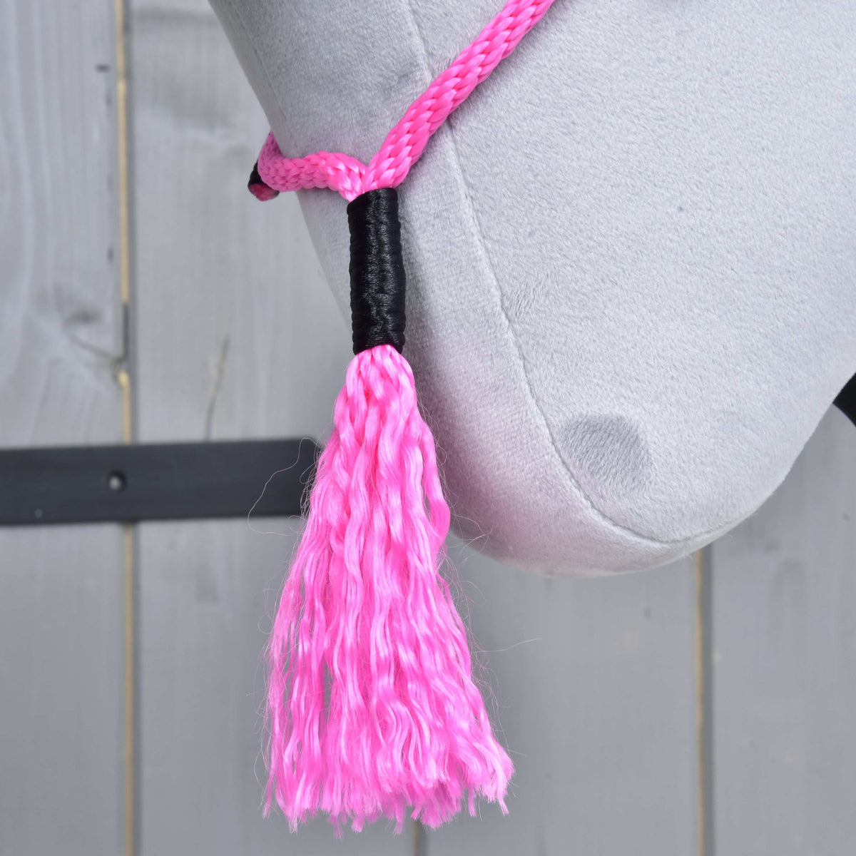 Pompon rose du cordéo Pink Festive au sommet enroulé de noir, suspendu sous la ganache d’un Hobby Horse gris