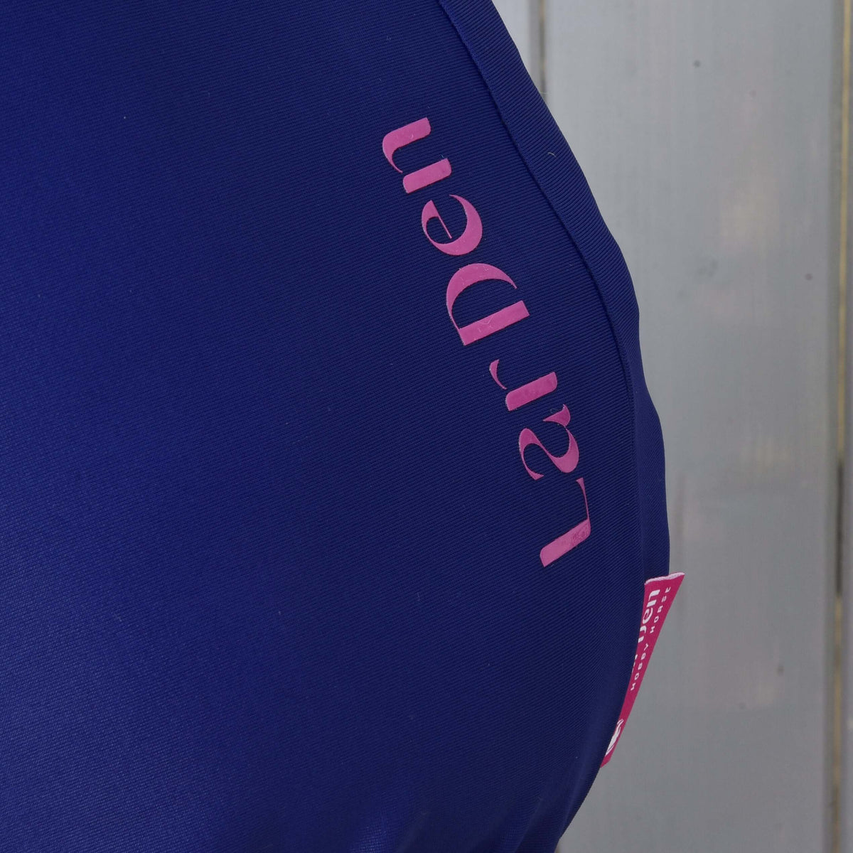 Close-up of the pink LarDen lettering and tag running down the neck of the navy Hobby Horse protective suit