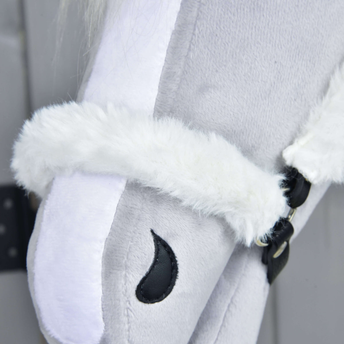 Close-up of the white fur noseband over the blaze, closed at the side with black leatherette straps and silver rivets