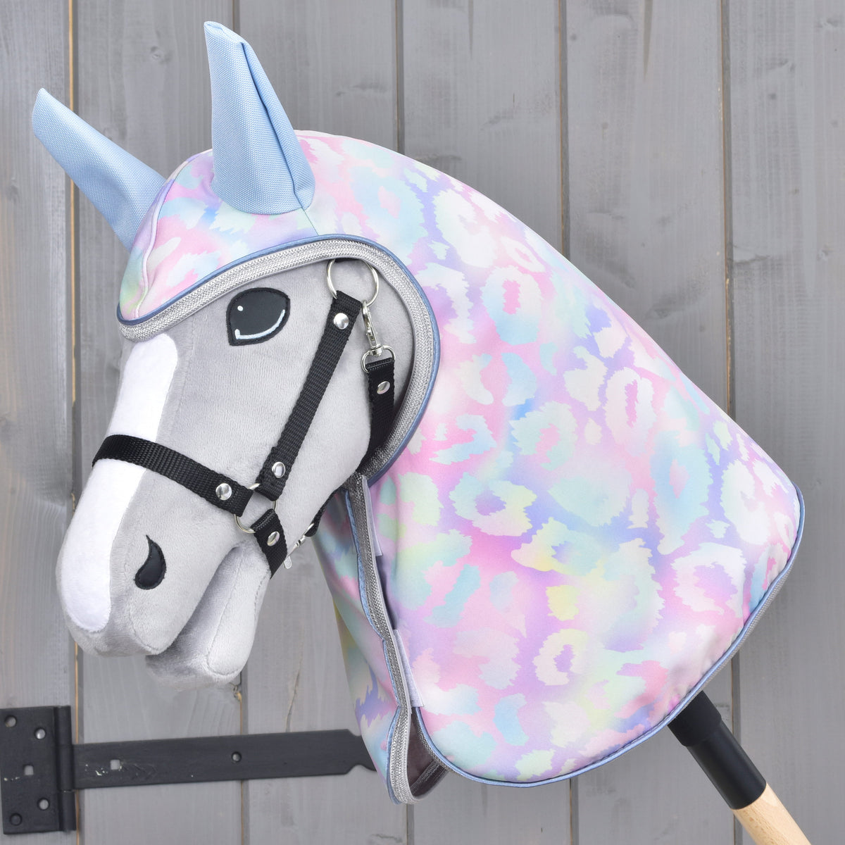Light grey Hobby Horse in a black halter wearing the Raincoat Pallette, pastel leopard print with light blue ears and silver trim