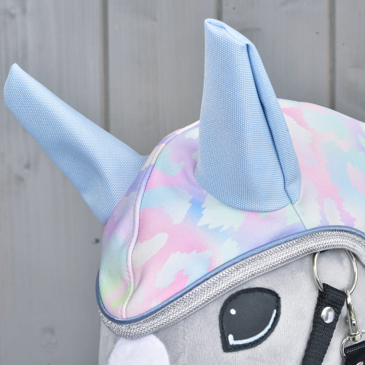 Close-up of the light blue woven ears on the Raincoat Pallette hood and silver glitter binding above a Hobby Horse eye