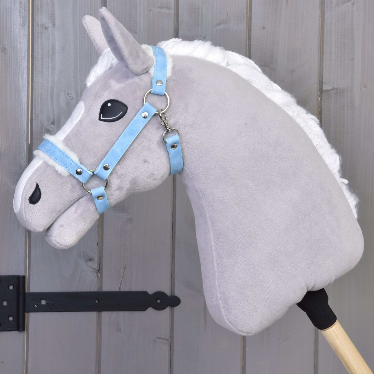 Grey Hobby Horse in left profile wearing the Halter with fur - leatherette Pastell Blue, its straps lined with white fur