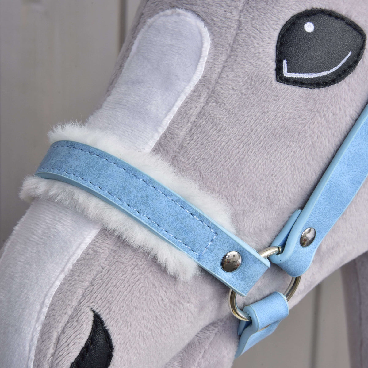 Close-up of the pastel blue leatherette noseband lined with soft white faux fur, with a silver ring and rivet