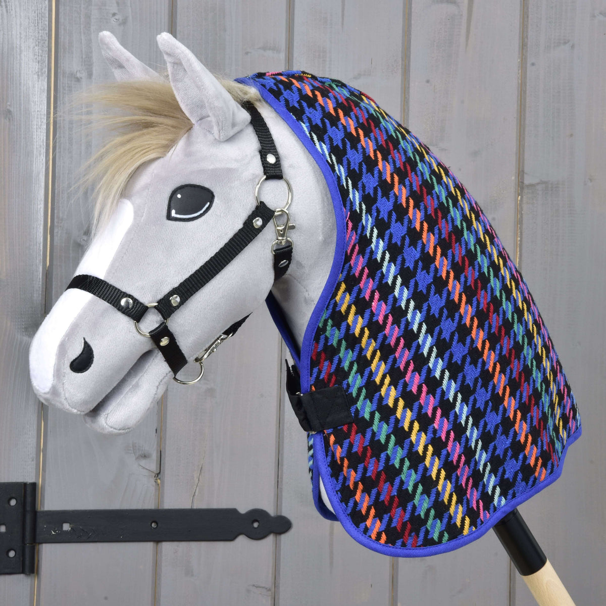 Hobby Horse gris à crinière blonde et licol noir portant la couverture d’écurie Peru pied-de-poule multicolore sur l’encolure