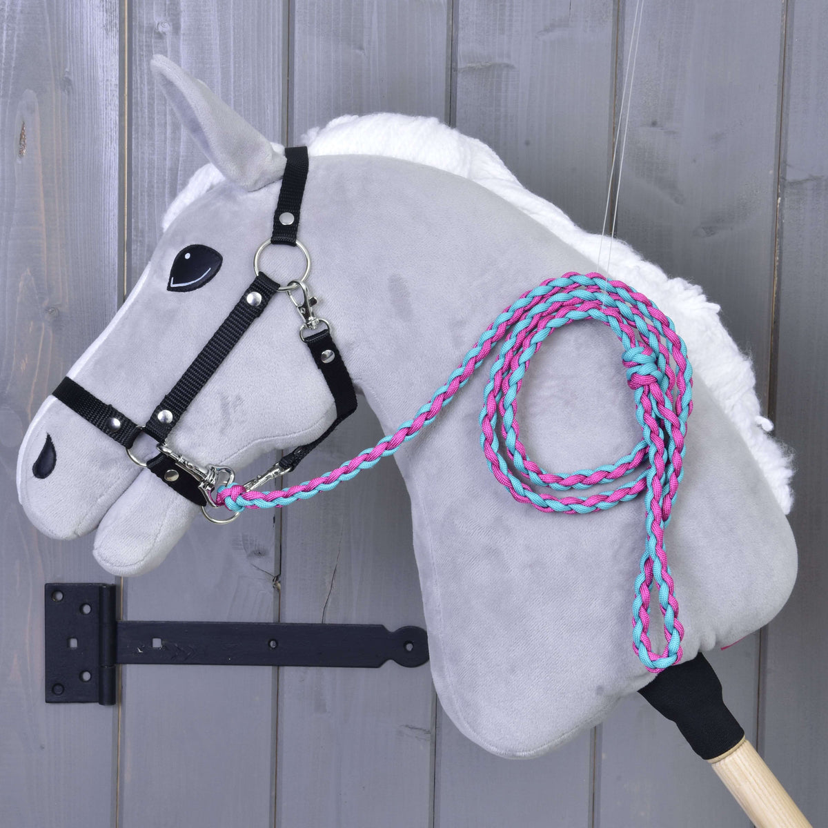 Grijze Hobby Horse met zwart halster en het roze-turquoise gevlochten halstertouw over de hals