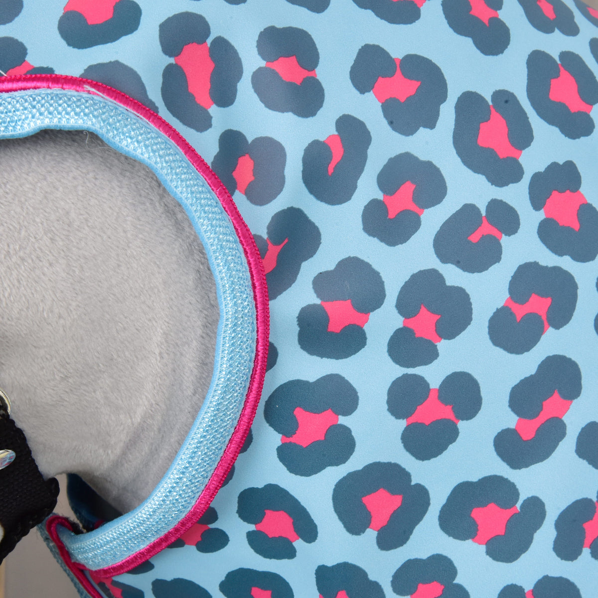 Close-up van de lichtblauwe stof met luipaardprint en de rand met roze bies rond de hoofdopening op grijs pluche