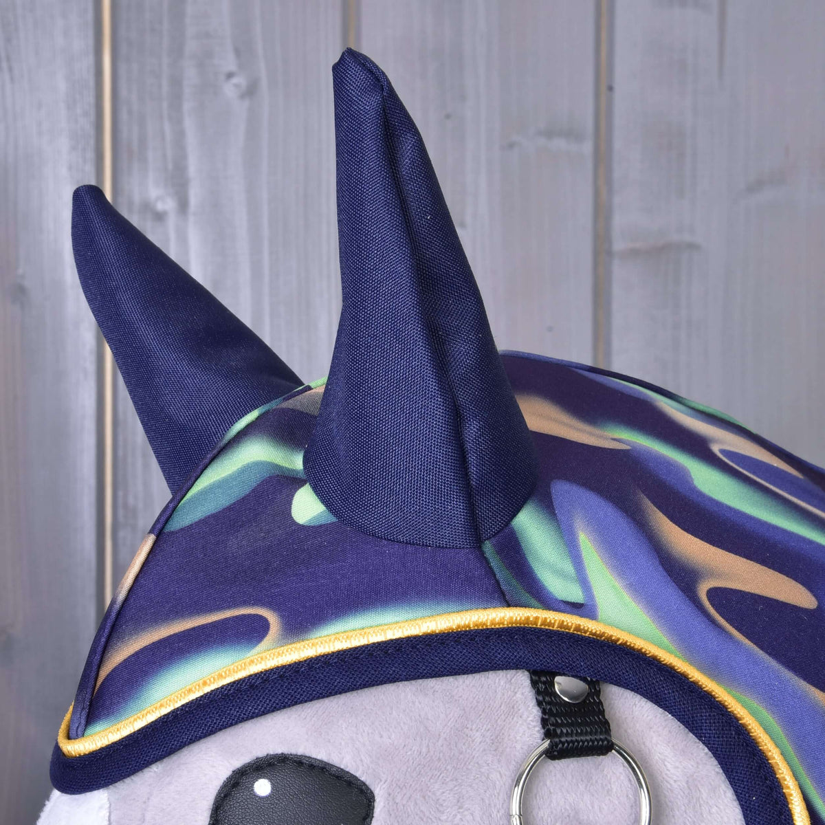 Gros plan des oreilles bleu marine et du motif ondulé menthe, lilas et beige à passepoil jaune de l’imperméable arc-en-ciel pour Hobby Horse