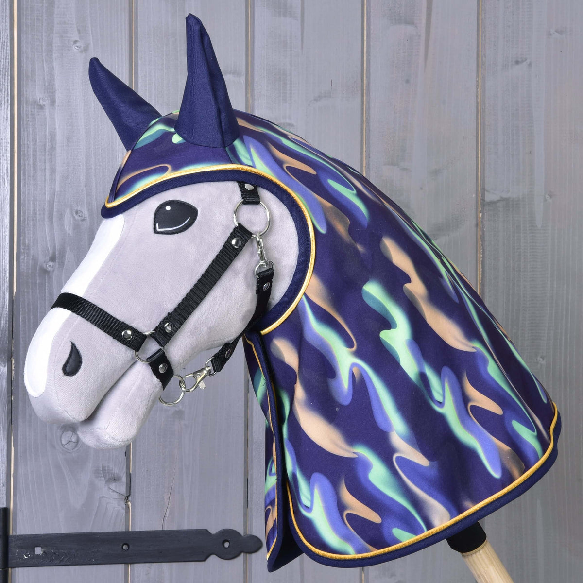 Hobby Horse gris avec licol noir portant l’imperméable arc-en-ciel, qui couvre la tête et l’encolure et a des oreilles bleu marine