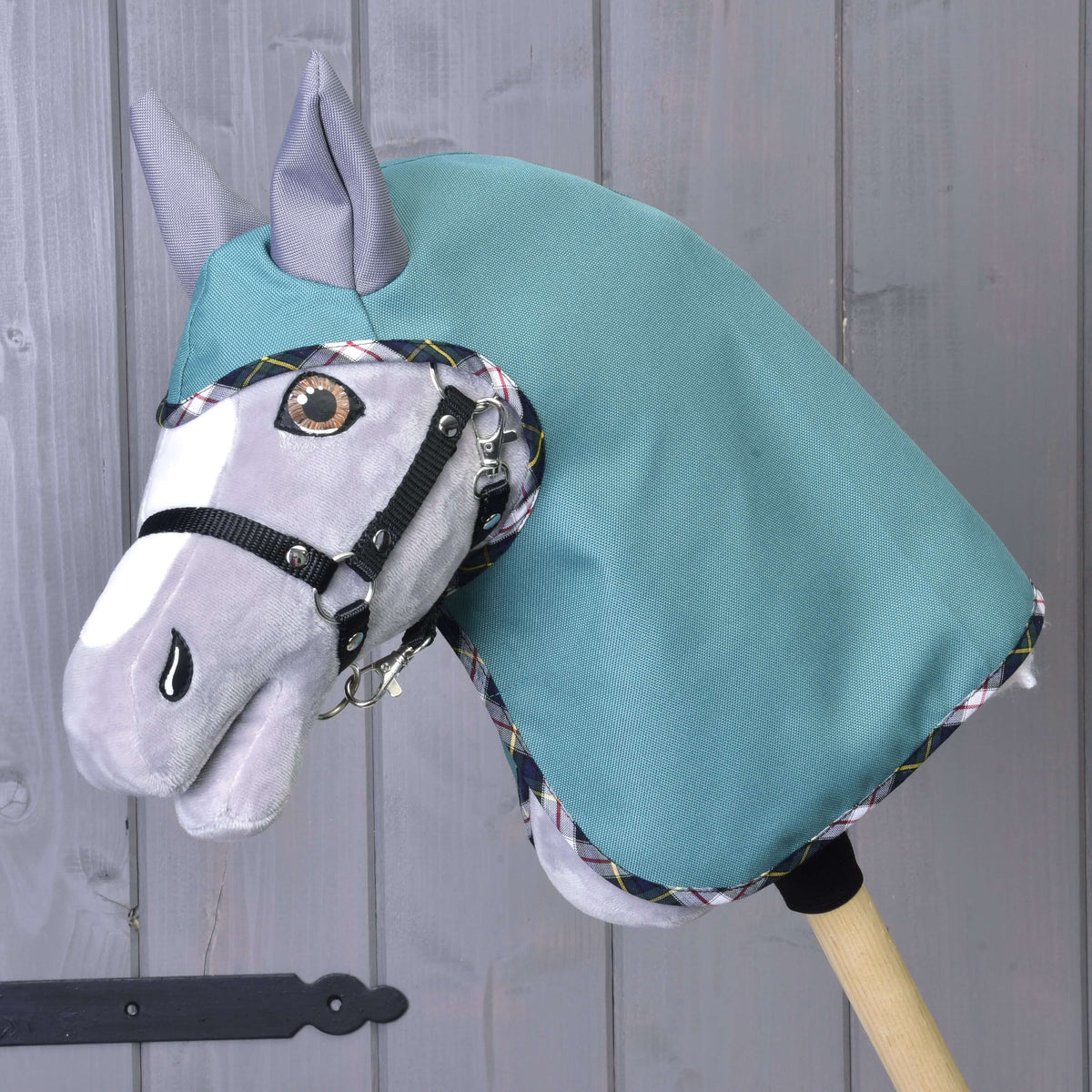 Hobby Horse gris portant l'imperméable d'été Émeraude vert d'eau avec oreilles grises et licol noir, vu de face