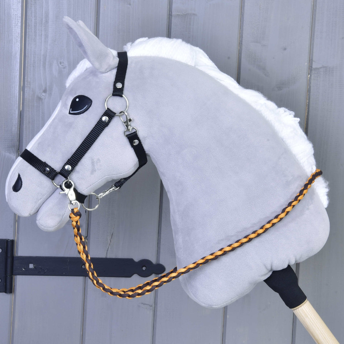 Grey plush Hobby Horse with a black halter and the orange and brown braided Pomello reins clipped under the chin