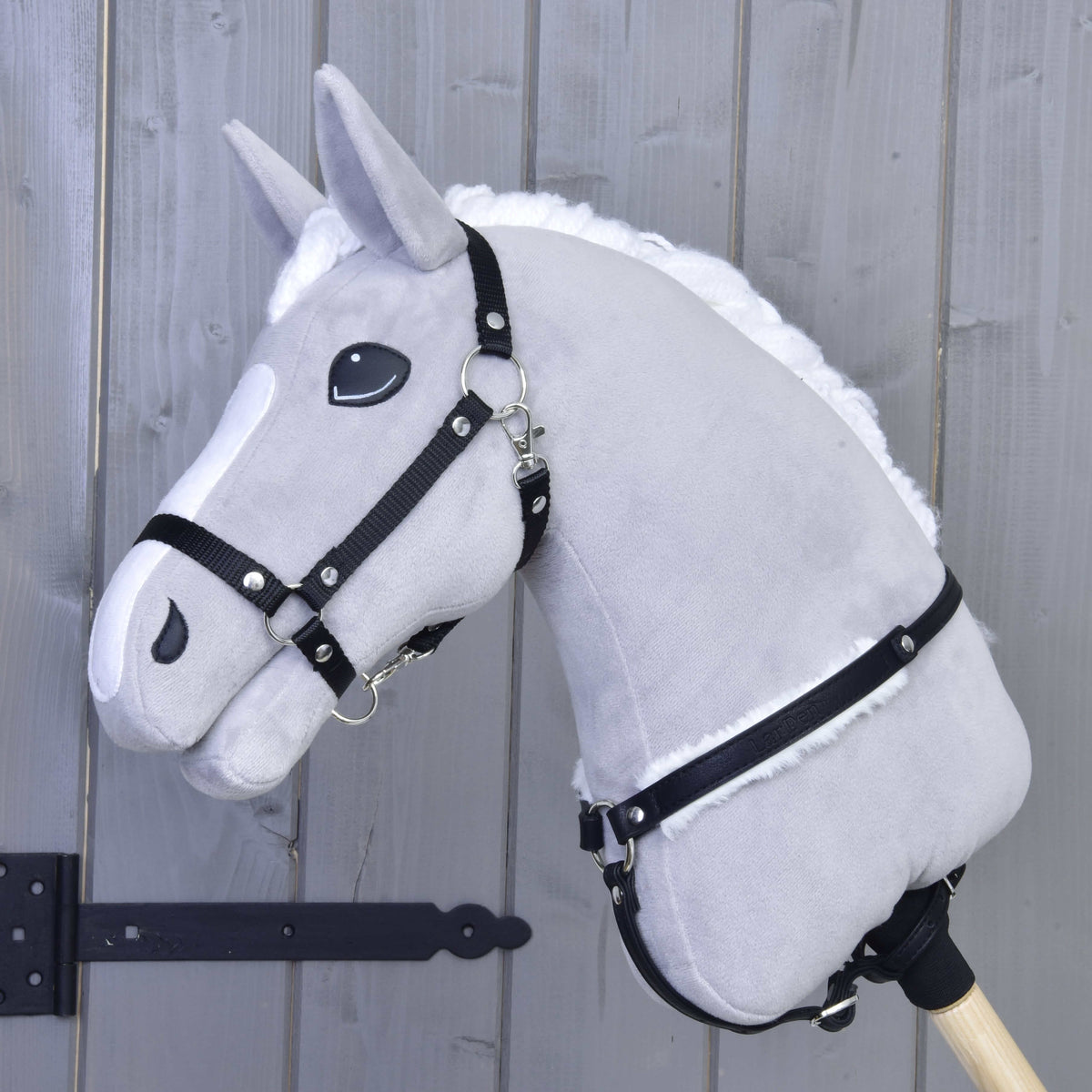 Lichtgrijze Hobby Horse met zwart halster en het zwarte borsttuig met wit bont onderaan de hals