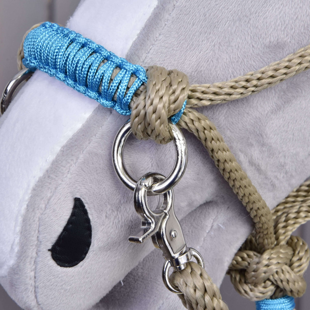 Macro detail of the blue cord braiding on the Hobby Horse Rope set Nature Blue noseband beside a beige knot and silver ring