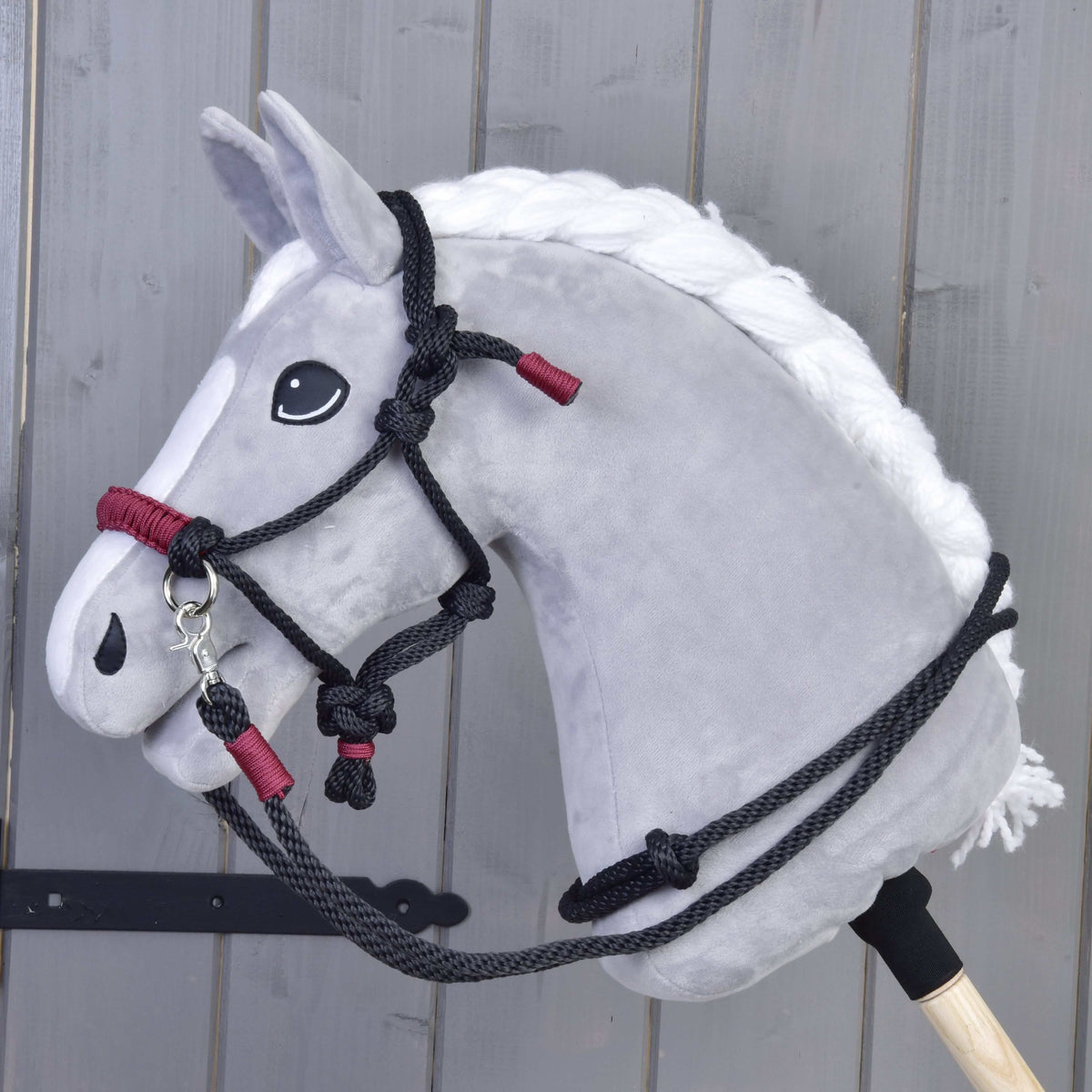 Hobby Horse gris à crinière blanche tressée portant l’ensemble de corde Maroon : licol en corde noir et rênes à bandes bordeaux