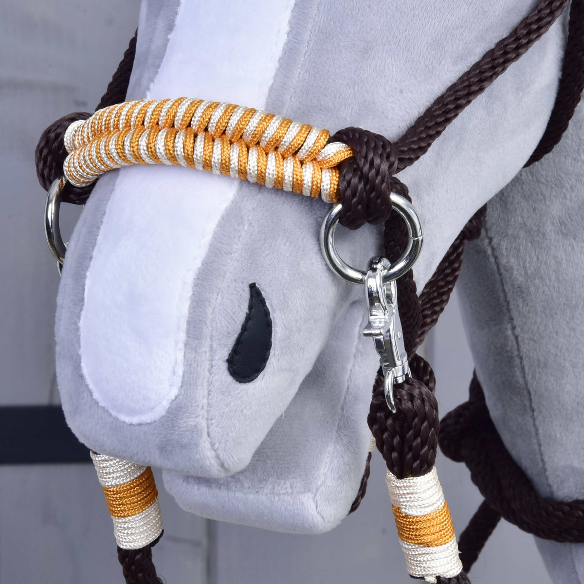 Detail van de neusriem van de Hobby Horse Touwset Oranje, gevlochten in oranje en wit, met zilveren ring en karabijnhaak