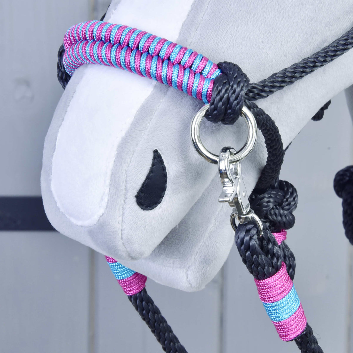 Gros plan sur la muserolle de l’ensemble de corde Princess pour Hobby Horse, tressée rose et turquoise, avec anneau et mousqueton