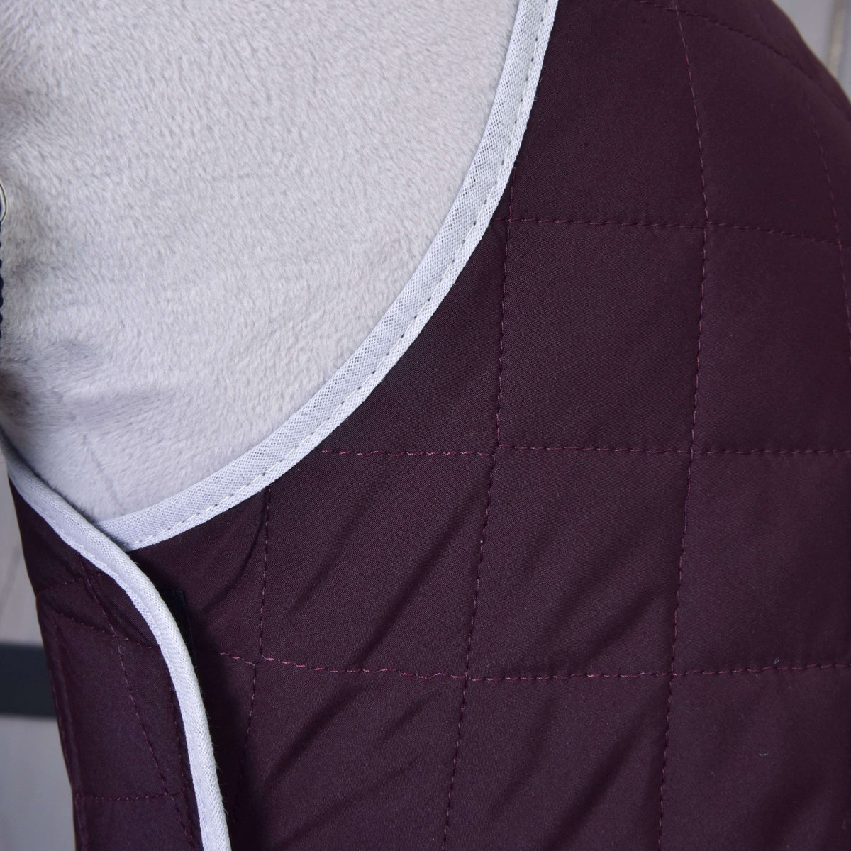 Close-up of the Set Purple blanket on a Hobby Horse: square-quilted dark purple fabric with light grey piping