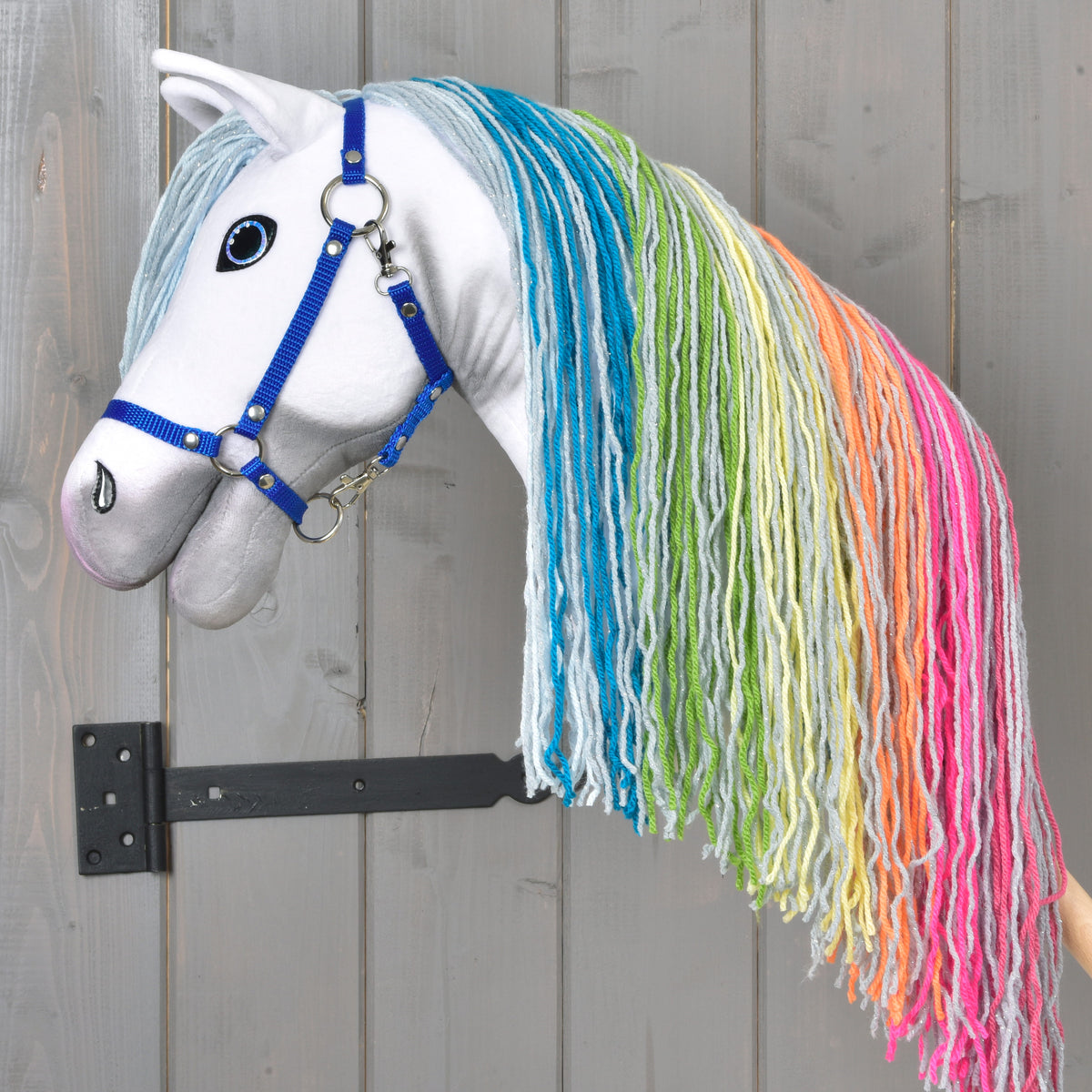 Hobby Horse Rainbow with head raised, its long mane in light blue, turquoise, green, yellow, orange and pink yarn