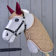 Grey Hobby Horse in a black halter wearing the beige quilted blanket and ear bonnet with burgundy ears