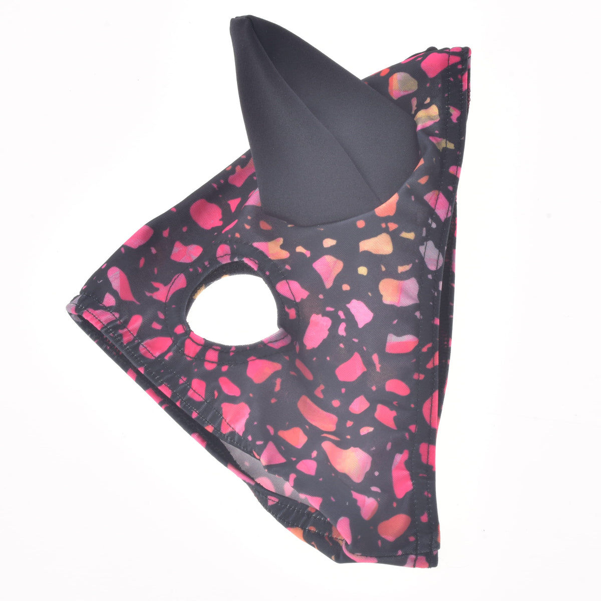 Masque pour cheval Roxy posé à plat, tissu extensible noir à éclats rose et corail, une oreille noire et une ouverture pour l’œil