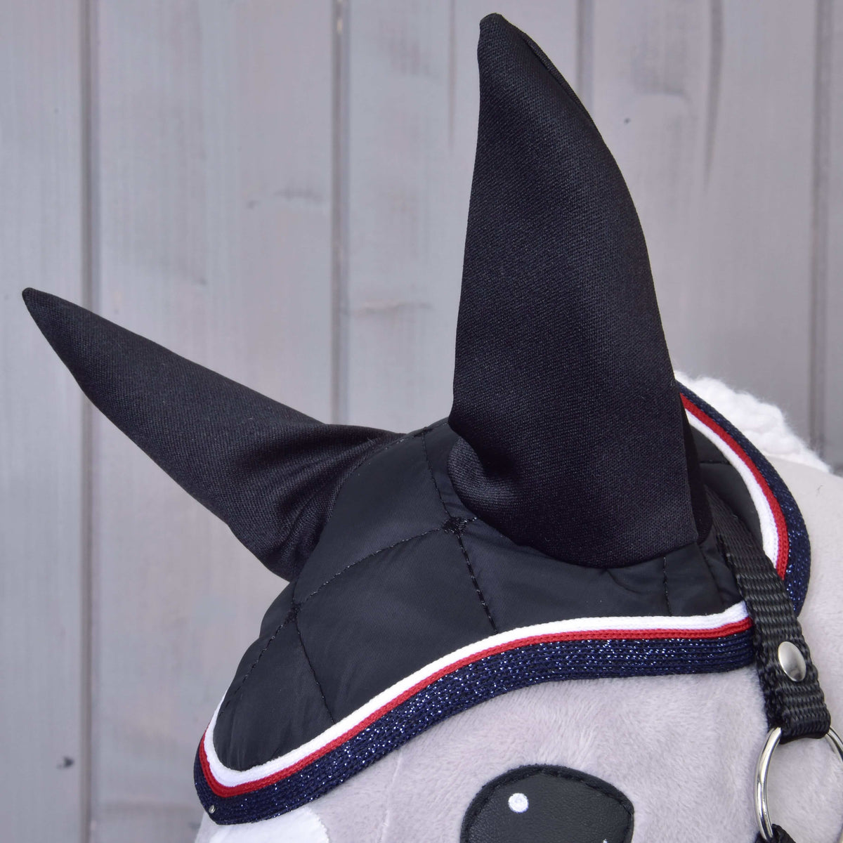 Gros plan sur le bonnet d’oreilles noir de l’ensemble Royal, hautes oreilles noires et bordure pailletée marine, rouge et blanche