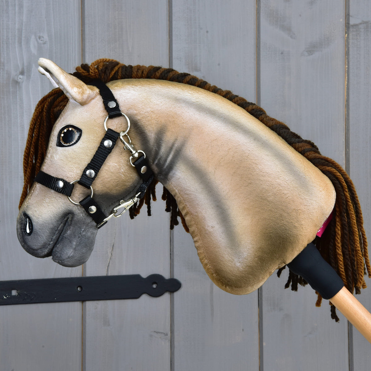 Hobby Horse Ruby vu de côté, encolure beige lisse ombrée de gris, mousqueton du licol et bâton en bois