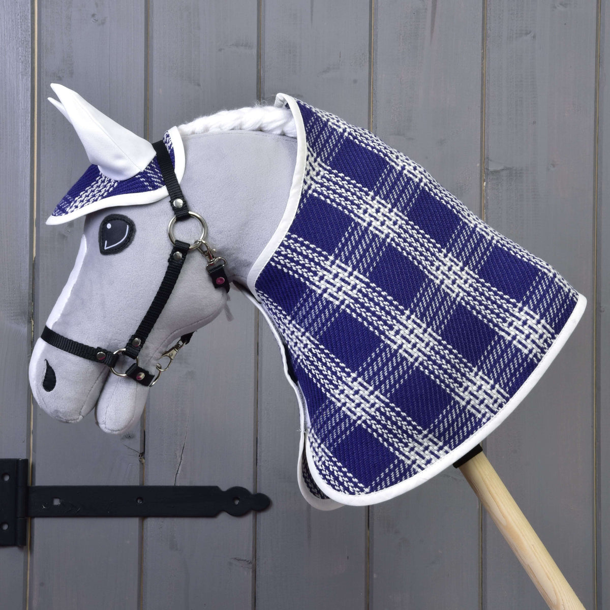 Vue de profil d'un Hobby Horse gris portant la couverture et le bonnet d'oreilles à carreaux bleus et blancs aux oreilles blanches