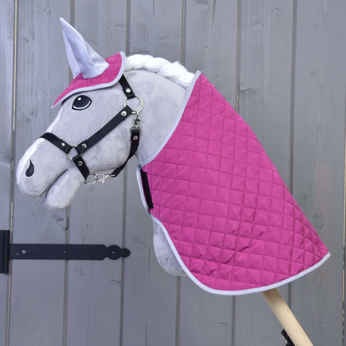 Grijze Hobby Horse met zwart halster in de gewatteerde felroze deken en het oornetje met zilveren oren