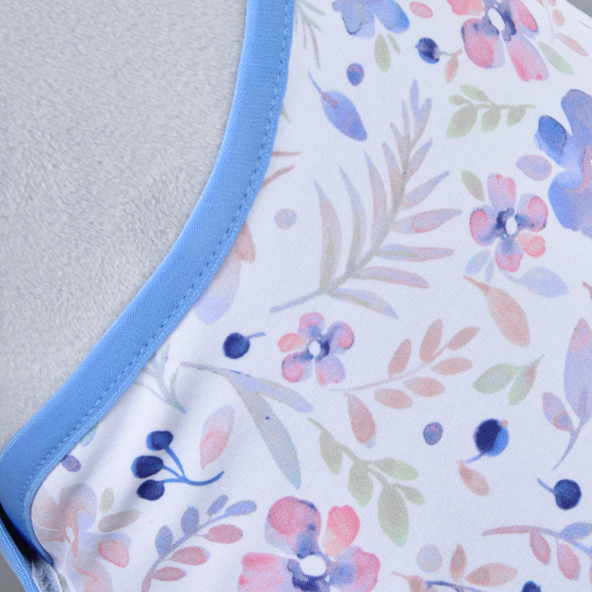 Close-up van de aquarelprint met roze, lila en donkerblauwe bloemen en zachte blaadjes, afgezet met korenblauw