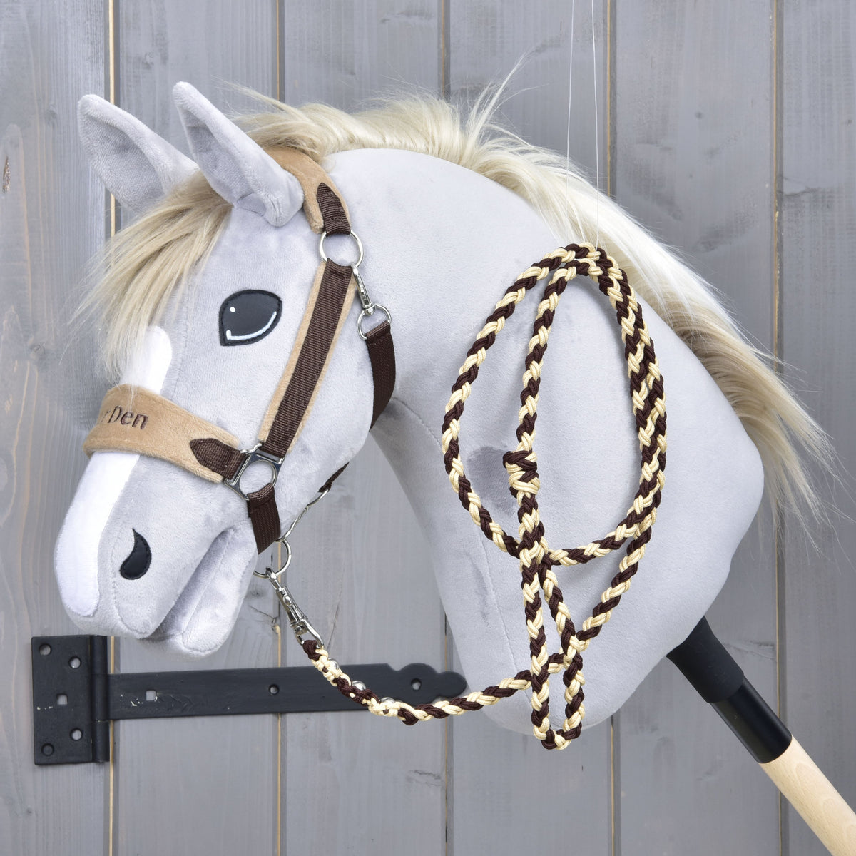 Hobby Horse gris avec le licol Exclusive Brown à muserolle beige brodée, la longe marron et crème posée sur l’encolure