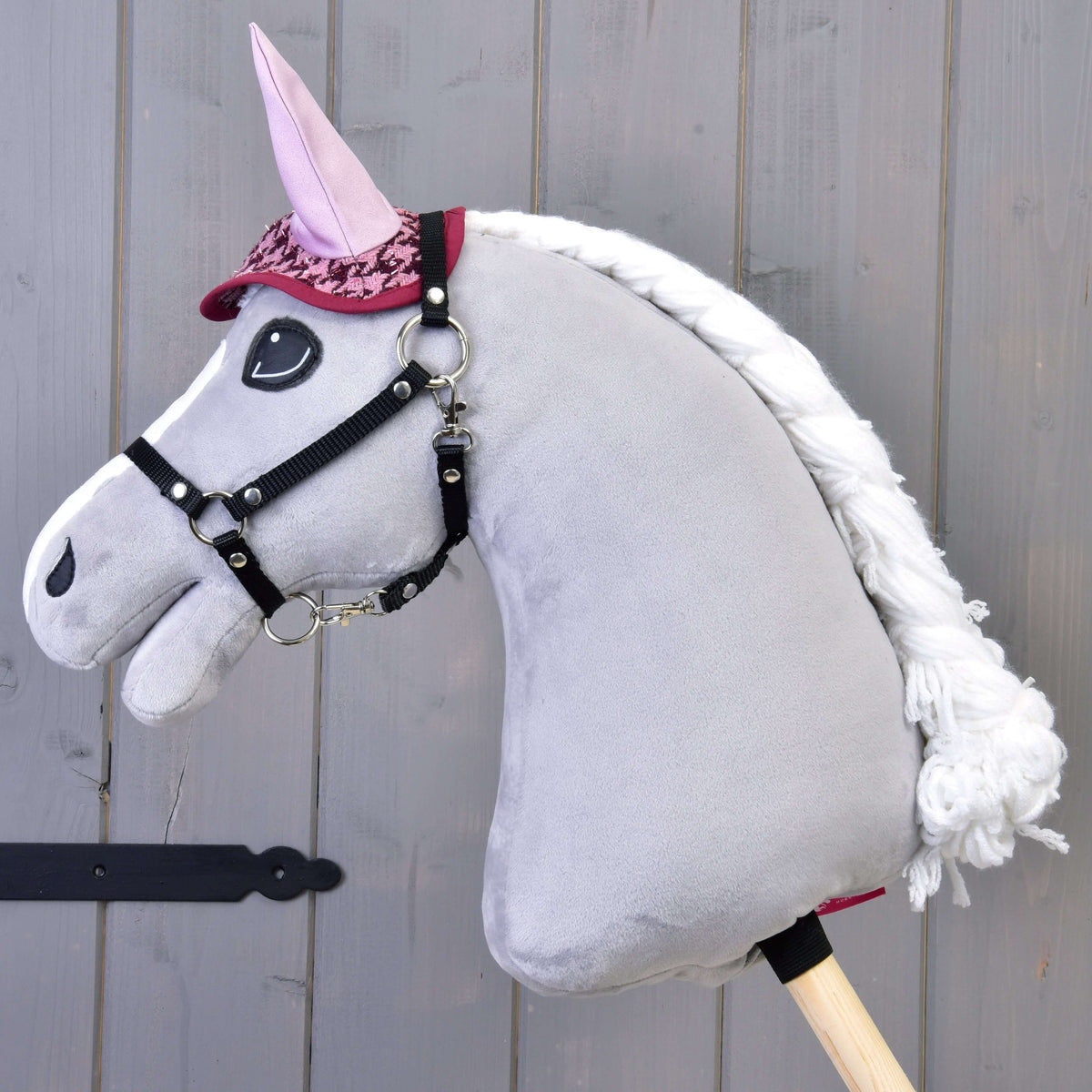 Grijze Hobby Horse met gevlochten witte manen die alleen het oornetje met pied-de-poule en lichtroze oren draagt