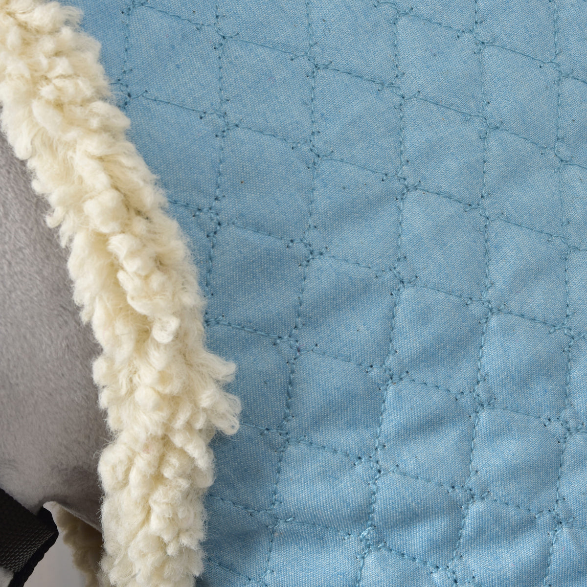 Detail van de krullende crèmekleurige fleecerand bij de hals en het stikwerk van de Hobby Horse staldeken Sky Blue