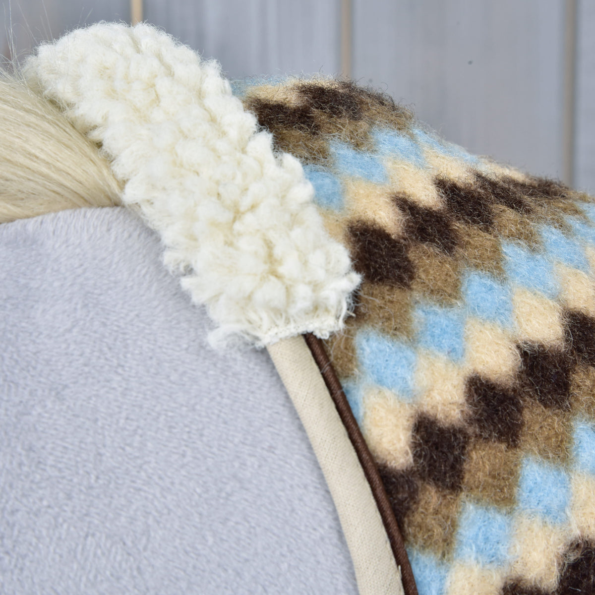 Close-up of the cream curly fleece collar and beige binding on the Stable Blanket Pastel Argyle on a grey Hobby Horse