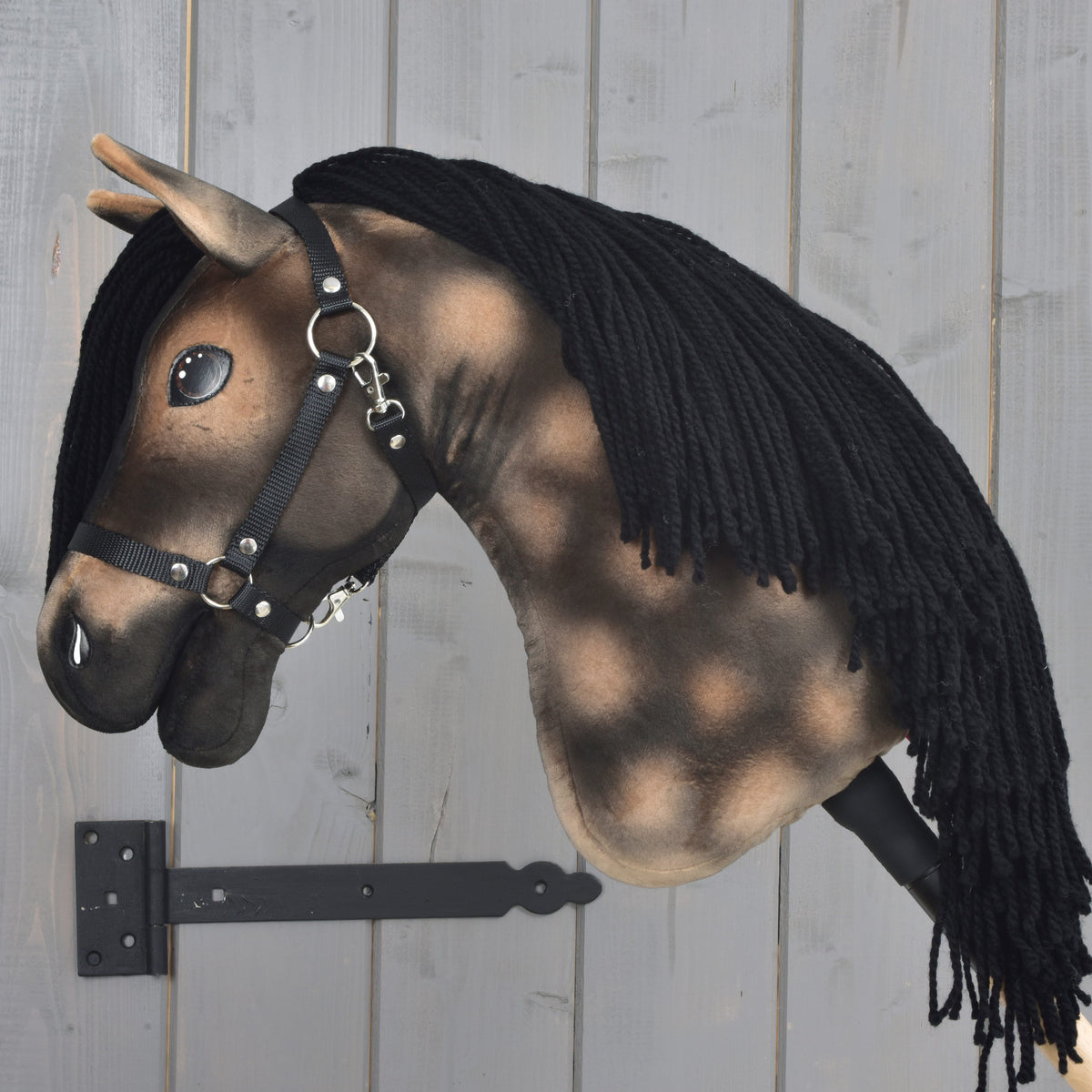 Hobby Horse Stormy avec licol noir vu de gauche, longue crinière en fil noir sur l’encolure pommelée jusqu’au bâton
